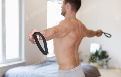 Preview: Shirtless Guy Exercising Stretching Resistance Rubber Band Loop Standing Indoors
