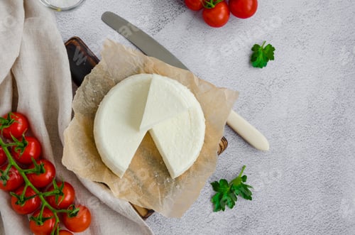 Preview: Homemade fresh soft cheese brynza or feta on a wooden cutting board with parsley and cherry tomatoes
