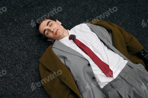 Preview: Handsome stylish man resting on carpet in a modern indoor setting during daytime
