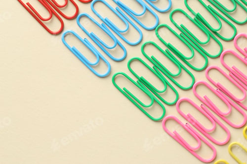 Preview: Colorful paper clips on beige background, flat lay. Space for text