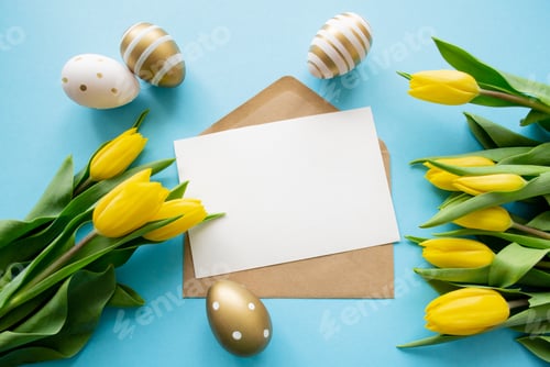 Preview: Easter greetings: yellow tulips, golden, white eggs on blue background. A letter copy space. Spring!