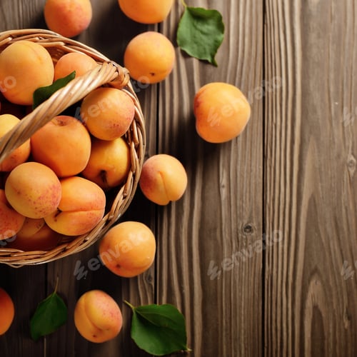 Preview: Top view of Wicker basket with ripe apricots on wooden table. Pl