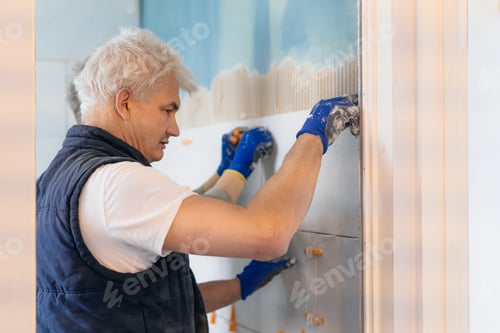 Preview: Father and son laying tiles on a bathroom wall. DIY concept. House improvement