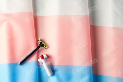 Preview: overhead shot of lipstick and a razor on a transgender flag