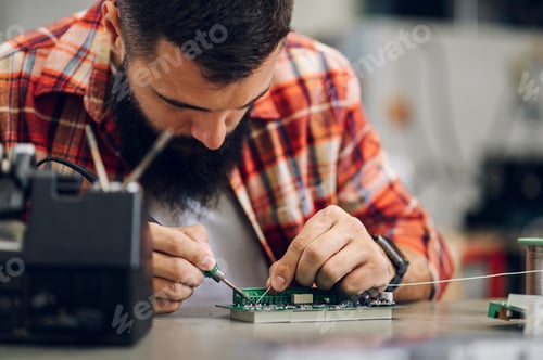 Preview: Electronics engineer working in a workshop with tin soldering parts