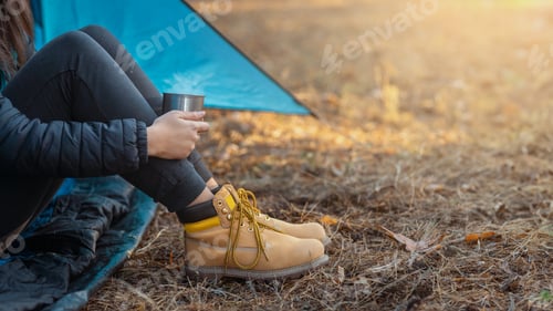 Preview: Legs in boots of woman camping in forest