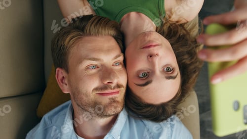 Preview: Cute lovers photographing smartphone chilling sofa closeup. Woman making selfie