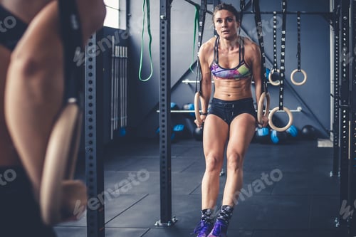 Preview: young athletic woman cross training gym using gymnastic rings