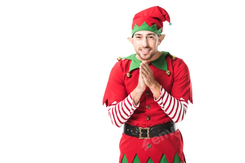 Preview: smiling man in christmas elf costume looking at camera and rubbing hands in anticipation isolated on