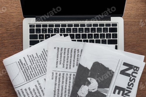 Preview: top view of newspapers and laptop on wooden tabletop