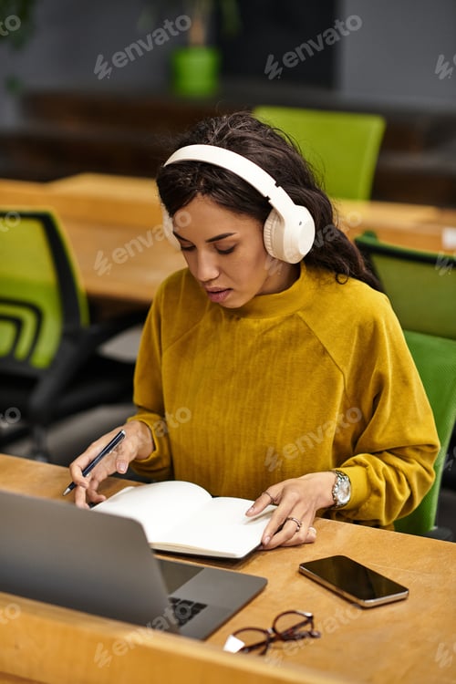 Preview: Elegant young woman engrossed in work at a modern office setting during daylight hours