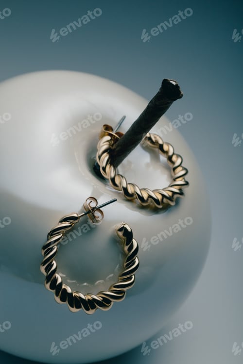 Preview: Gold hoop earrings placed in vintage aesthetic, showcasing modern jewelry, copy space.