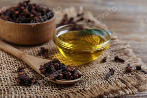 Preview: Essential oil and dried cloves on wooden table, closeup