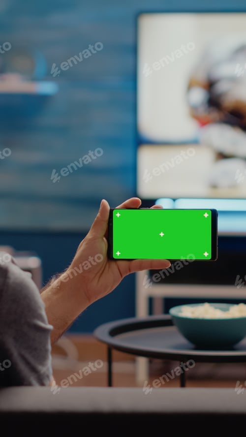 Preview: Young man watching horizontal green screen on smartphone