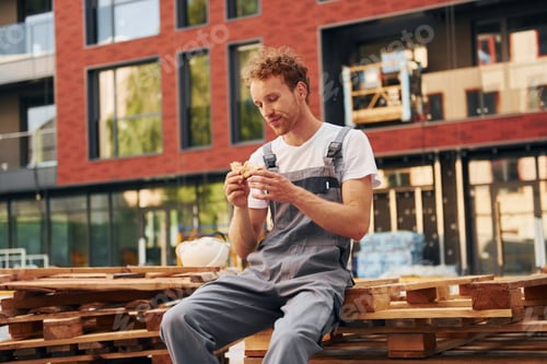 Preview: Building exterior. Young man working in uniform at construction at daytime
