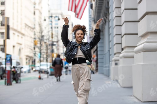 Preview: Woman dancing and playing on city sidewalk listening to music.