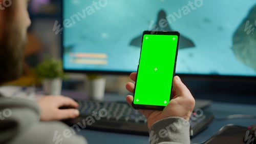Preview: Competitive gamer looking at smartphone with green screen display