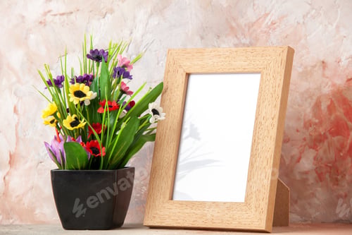 Preview: Close up view of brown empty wooden photo frame and beautiful flower pot on pastel colors background
