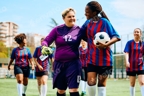 Preview: Happy female soccer players walking on playing field after sports training.