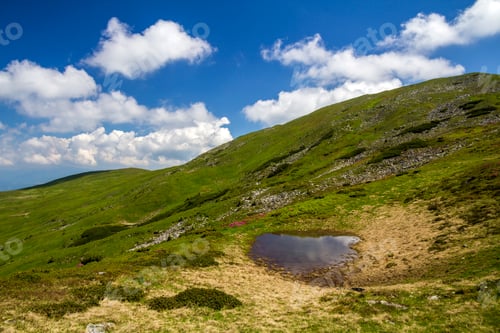 Preview: Blue sky with bright white clouds reflected in small lake