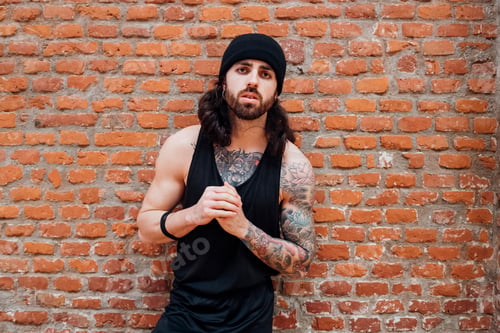 Preview: Focused man in athletic gear ready for a workout against a brick wall backdrop.