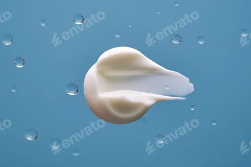 Preview: Swatch with white cream texture on a blue background with water drops.