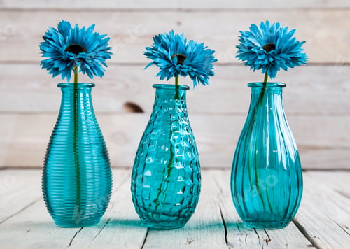 Vista previa: blue gerbera flower in a vase on wooden background