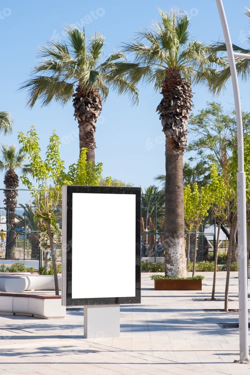 Visualização: Um grande quadro publicitário em branco fica em um parque ensolarado com palmeiras