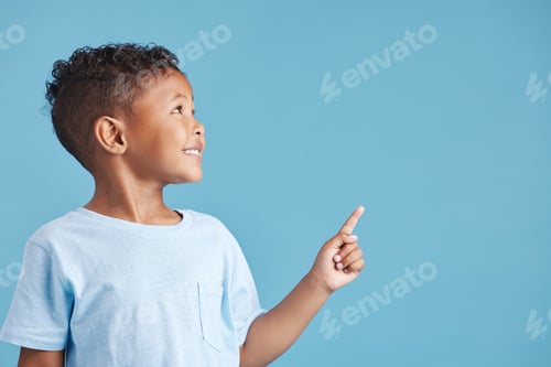 Preview: Close up of a happy smiling little boy looking up and pointing his finger at copy space to the righ