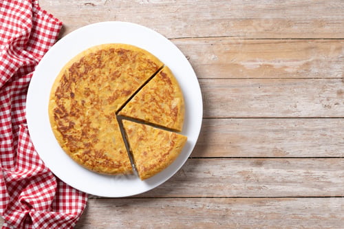 Preview: Traditional spanish omelette with ingredients on wooden table.