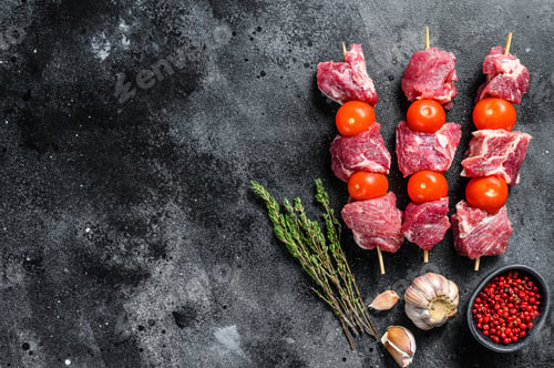 Preview: Raw pork shish kebab. BBQ meat with tomato and spices. Black background. Top view. Copy space