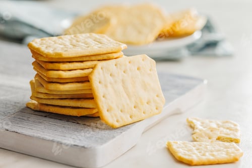 Preview: Golden Baked Crackers on cutting board on a White kitchen table.