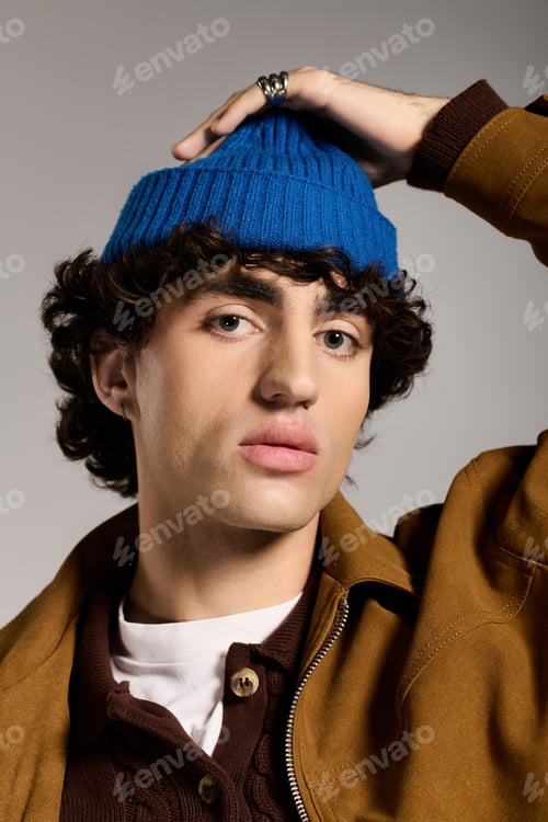 Preview: Handsome young man confidently poses, wearing a blue beanie and fashionable attire, bringing charm