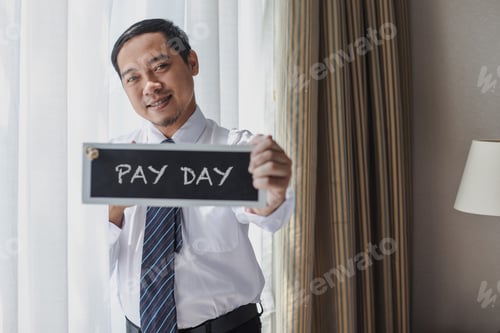 Man Holding Pay Day Sign in Bright Room