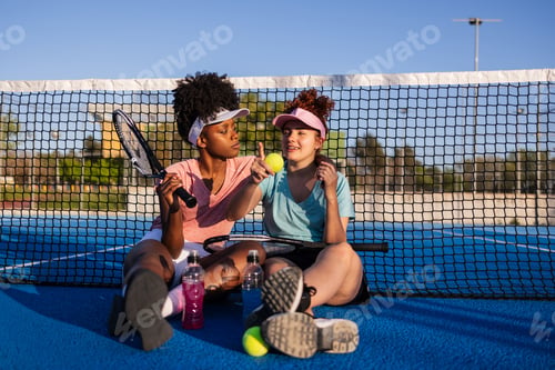 Preview: Two female tennis players resting after training on a paddle tennis court