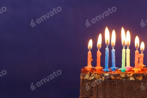 Visualização: Bolo de brownie de feliz aniversário com amendoim, caramelo salgado e velas coloridas acesas na violeta