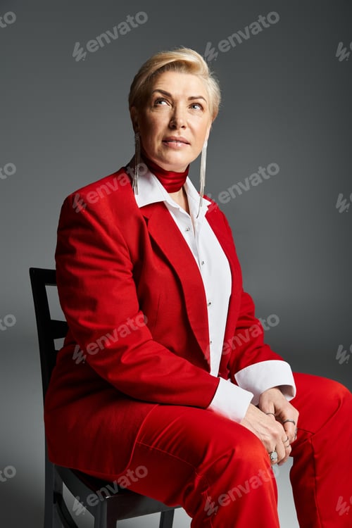 Preview: Stylish adult woman in elegant red attire poses gracefully in a modern studio setting