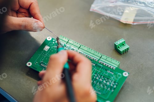 Preview: Electronics engineer hands working in a workshop with tin soldering parts