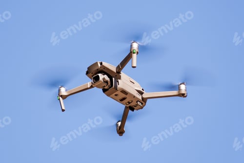 Preview: Close up of flying drone quad-copter with digital camera; blue sky background