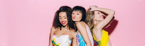 Preview: panoramic shot of happy fashionable multicultural girlfriends dancing on pink