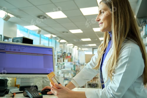 Preview: young pharmacist girl dispensing a medicine on the computer in a pharmacy
