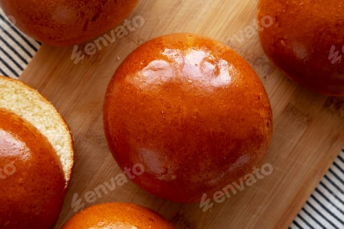 Preview: Homemade Brioche Hamburger Buns on a wooden board, top view. Flat lay, overhead, from above.
