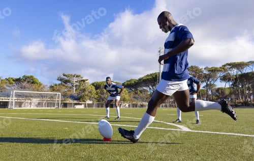 Preview: Three African American young male athletes training with a rugby ball on a field outdoors