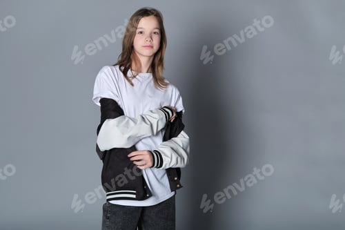 Preview: A girl stands in a relaxed pose with her jacket over her shoulders, gazing down
