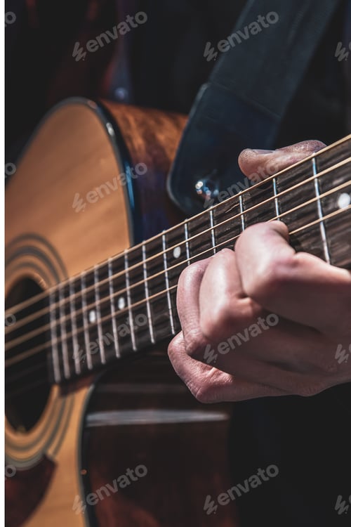 Preview: Guitarist playing acoustic guitar in the dark close up.