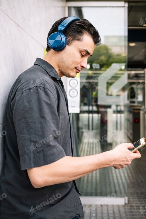 Preview: Man using smartphone outside modern building