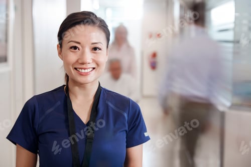 Preview: Portrait Of Smiling Female Nurse Wearing Scrubs In Busy Hospital Corridor