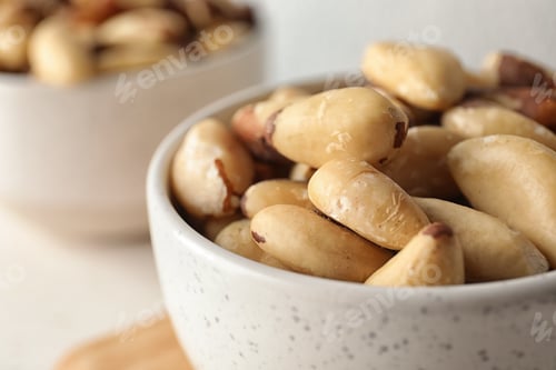 Preview: Bowl with tasty Brazil nuts on table, closeup