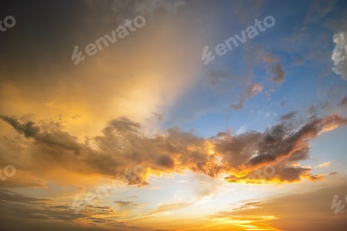 Preview: Dramatic sky at sunset with puffy clouds lit by orange setting sun.
