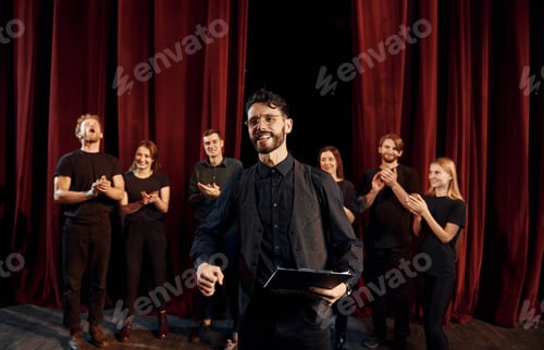 Preview: Man is practicing his role. Group of actors in dark colored clothes on rehearsal in the theater